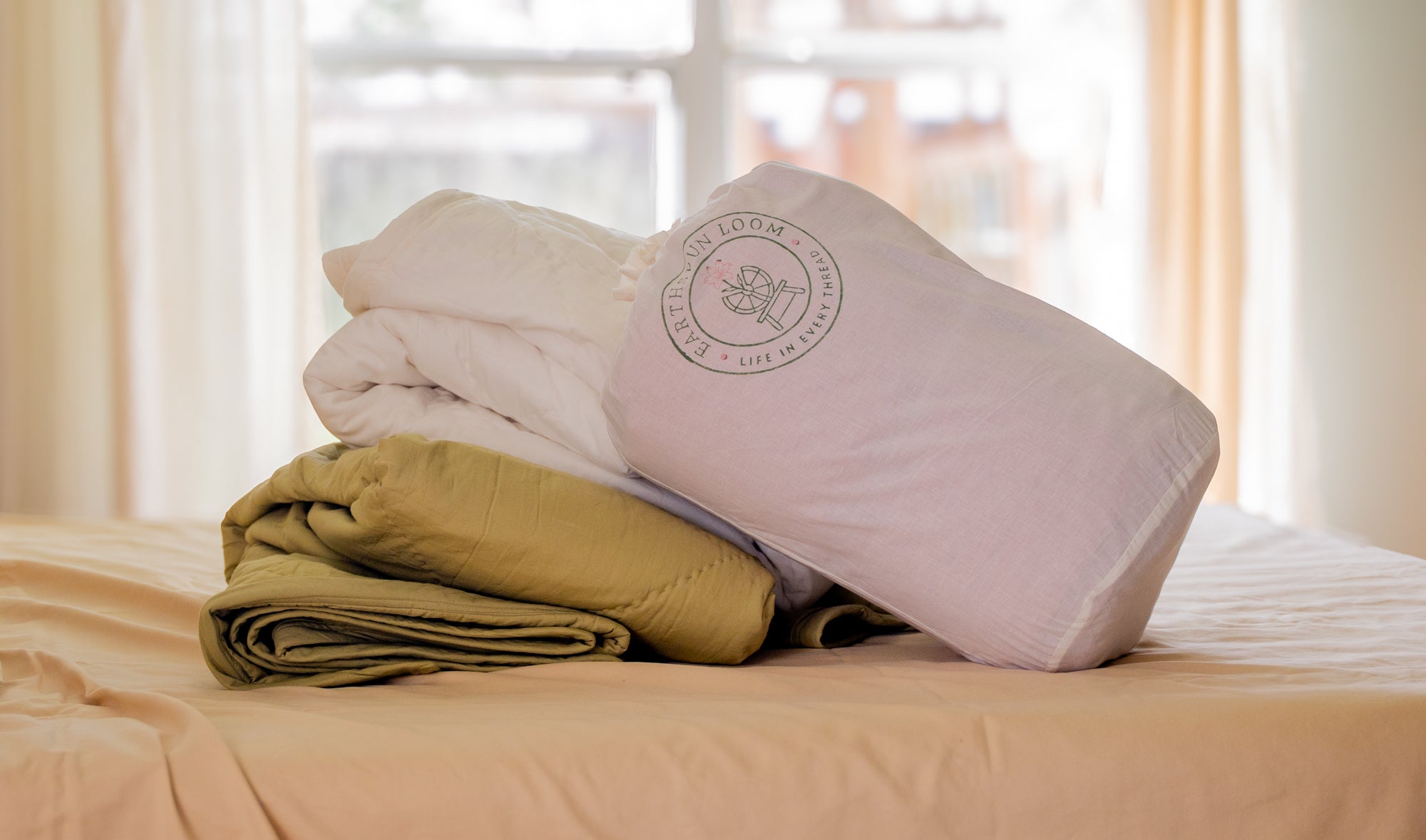 organic cotton lightweight all-season comforters in natural storage bag, styled on a bed in a naturally minded home